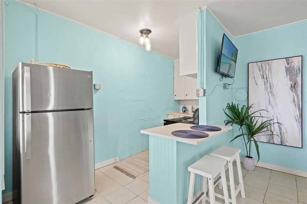 A kitchen features light blue walls, a stainless steel refrigerator, and a small breakfast bar — 1303 S BERMUDA BOULEVARD, TAMPA, FL
