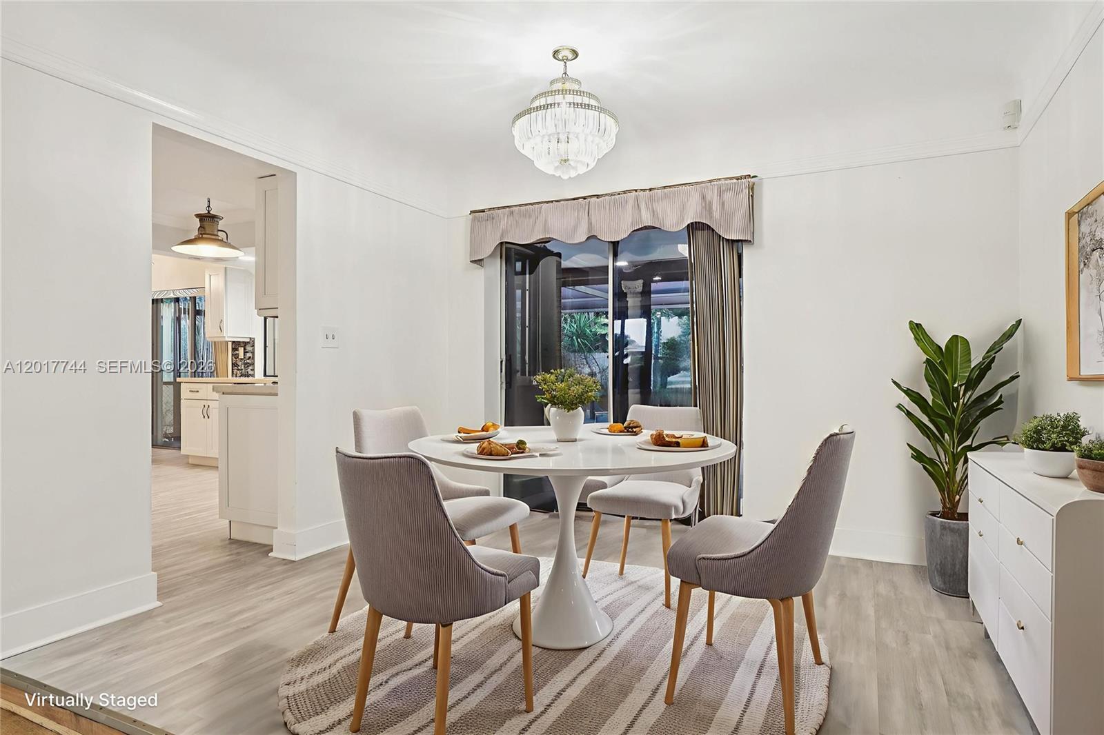 A dining room features a round white table, four chairs, and a crystal chandelier — 3842 Jasmine Avenue, Miramar FL 33023, MIRAMAR, FL