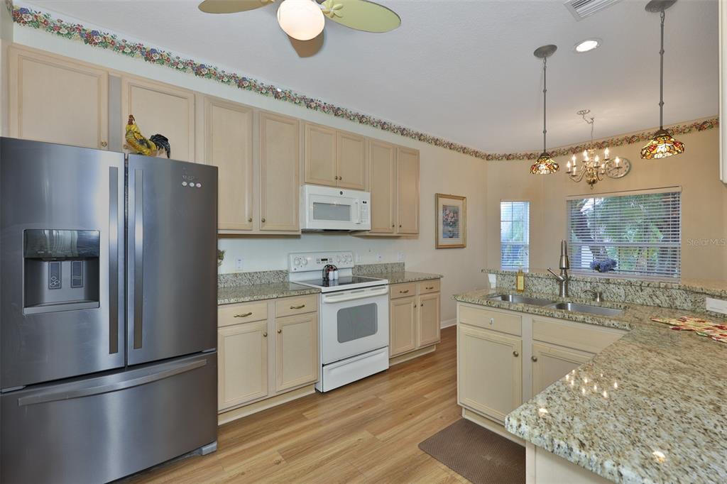 A kitchen with light-colored cabinets, granite countertops, stainless steel appliances, and wood-look flooring — 4465 STRATHMORE DRIVE, LAKE WALES, FL