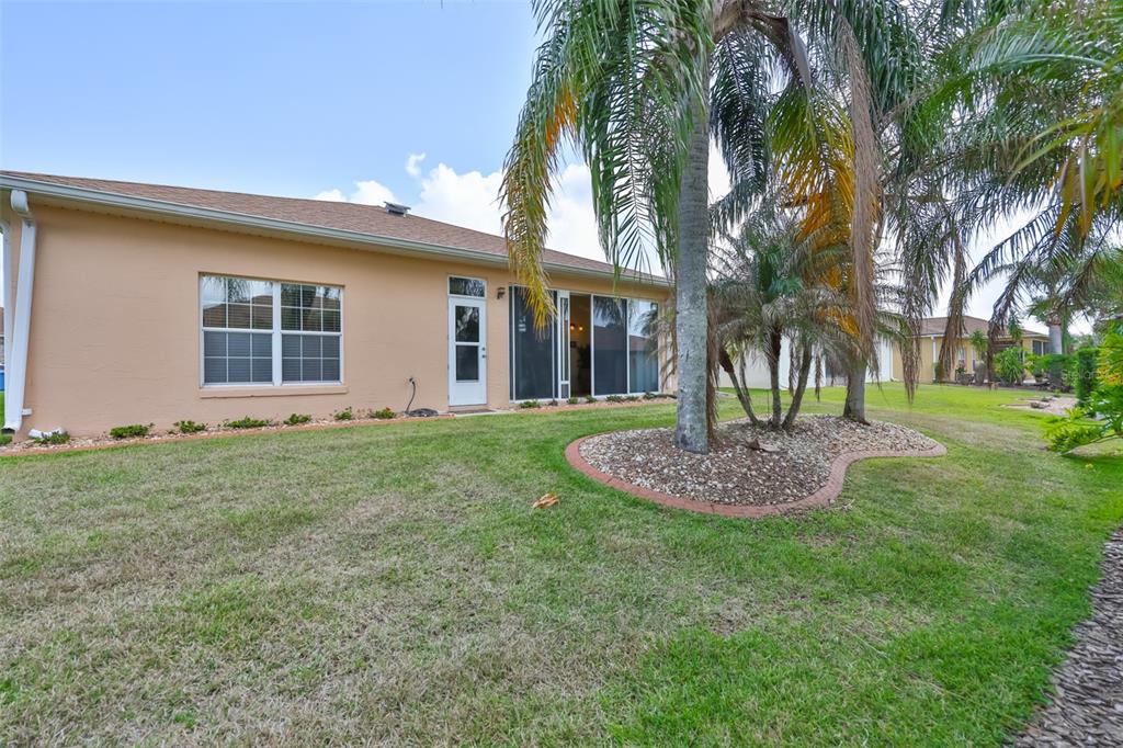 The exterior of a peach-colored house features a lawn, palm trees, and a rock garden — 4465 STRATHMORE DRIVE, LAKE WALES, FL
