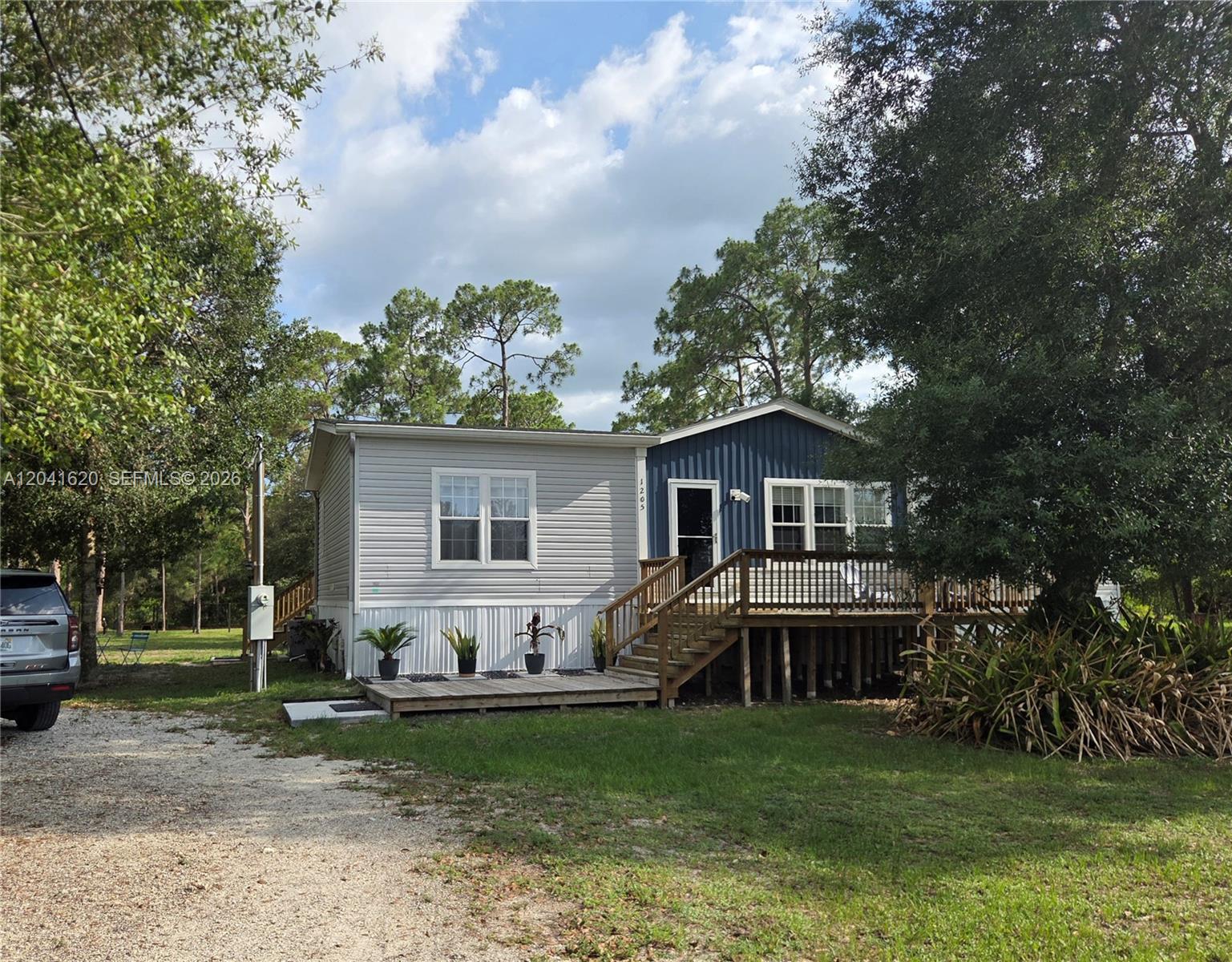 A single-story house with light gray siding, a blue accent wall, and a wooden deck — OTHER CITY - IN THE STATE OF FLORIDA, FL