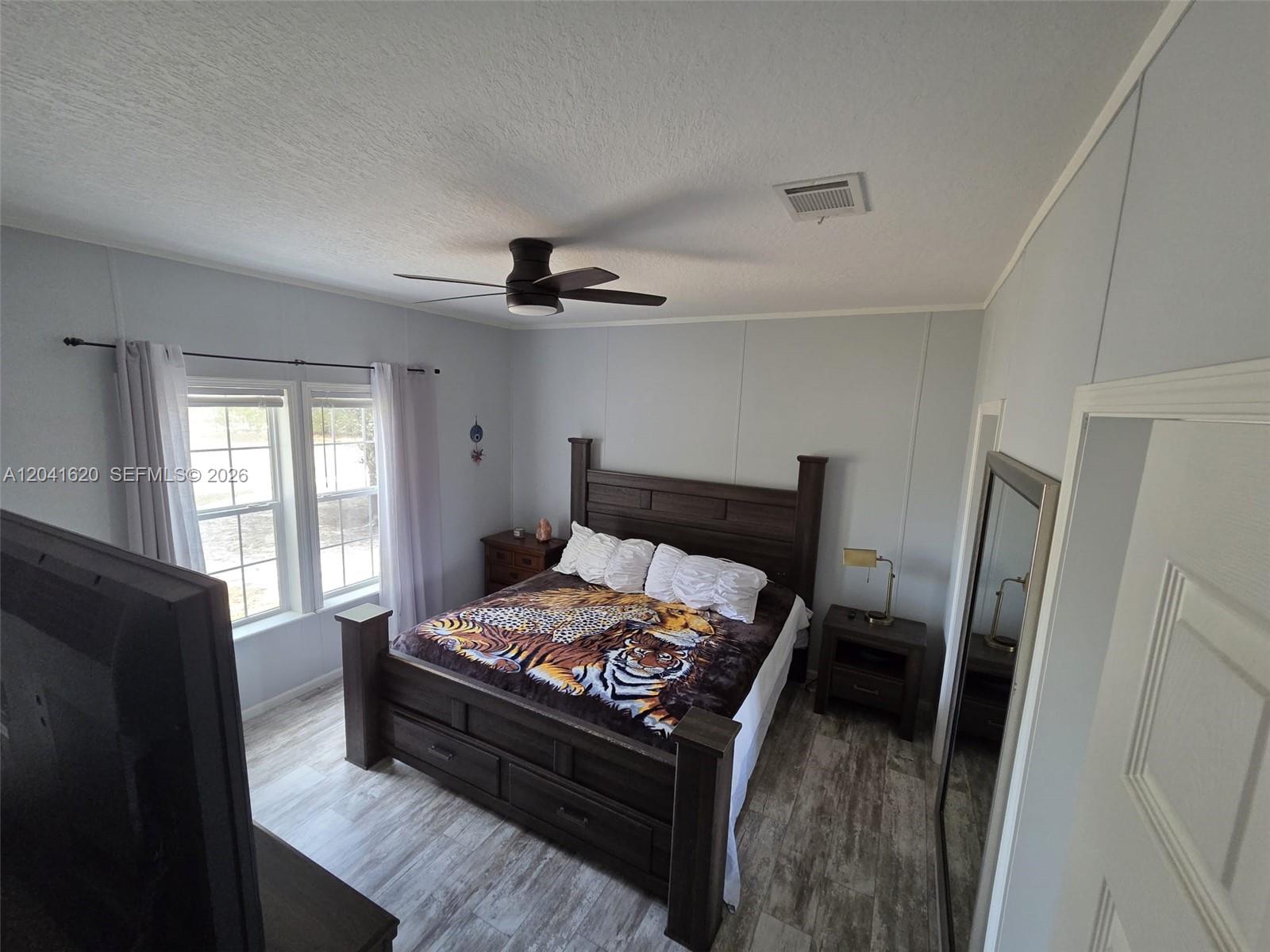 A bedroom features a dark wood bed frame, a tiger-print blanket, and light-colored flooring — OTHER CITY - IN THE STATE OF FLORIDA, FL