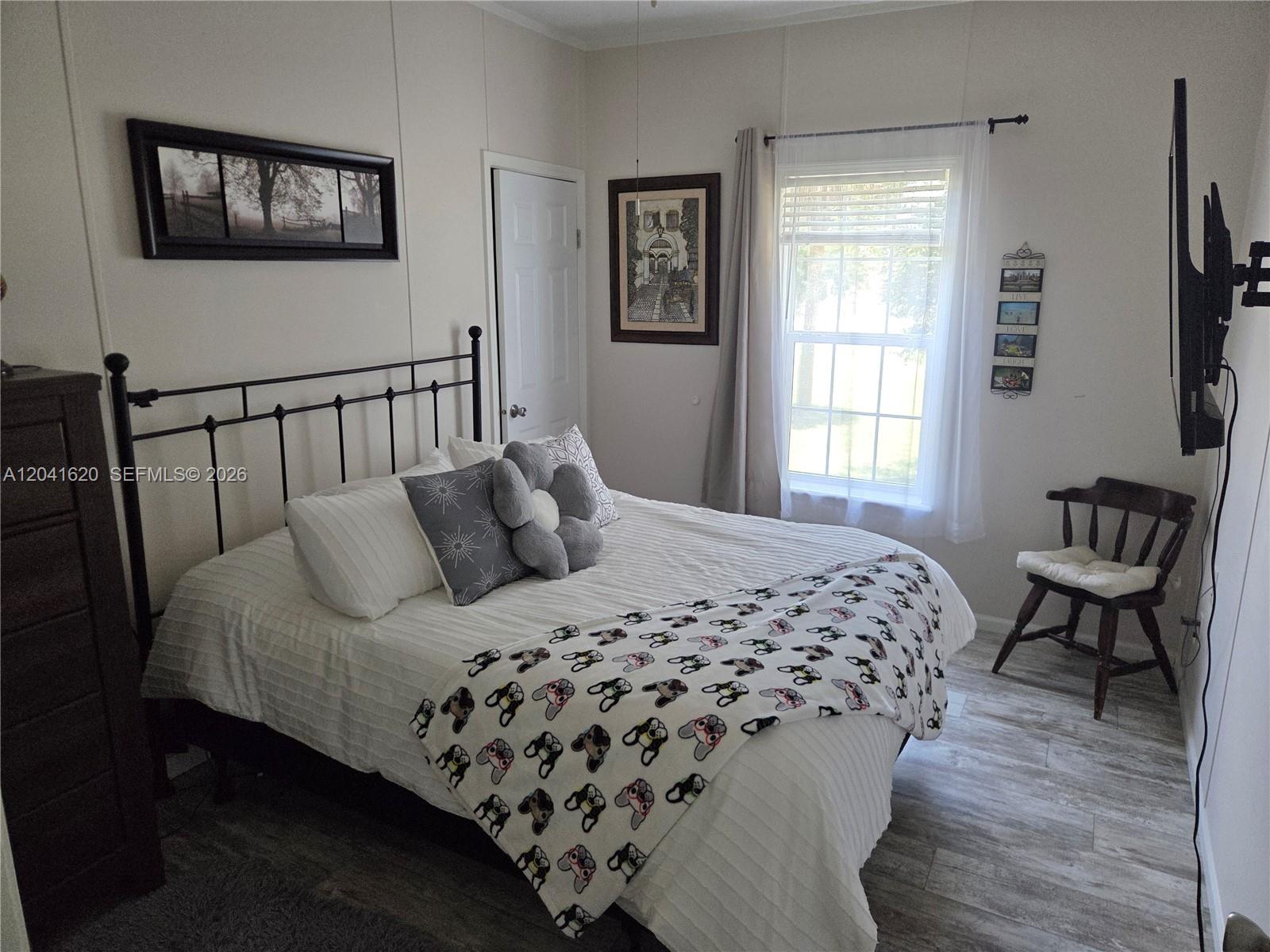 A bedroom features a metal bed frame, white bedding, a window, and a wooden chair — OTHER CITY - IN THE STATE OF FLORIDA, FL