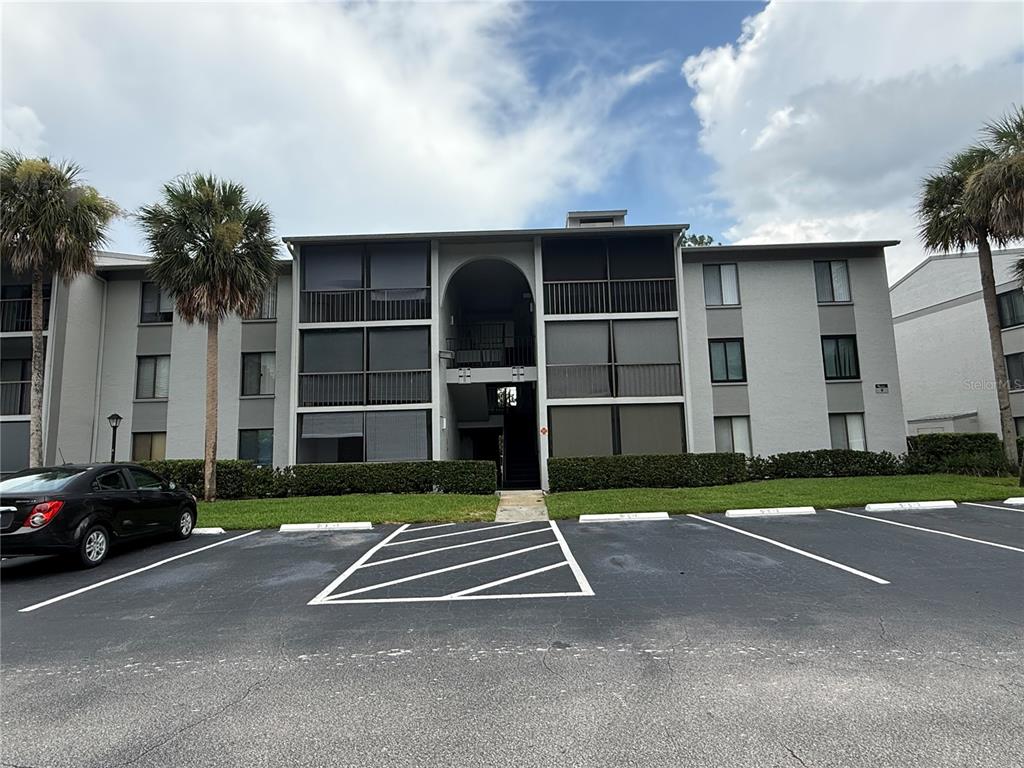 A three-story apartment building with screened balconies and a parking lot in the foreground — 927 S PINE RIDGE CIRCLE UNIT G2, SANFORD, FL