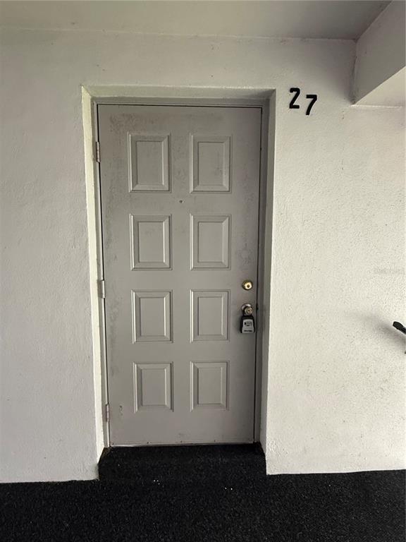 A gray door with a lockbox and the number 27 above it on a white wall — 927 S PINE RIDGE CIRCLE UNIT G2, SANFORD, FL