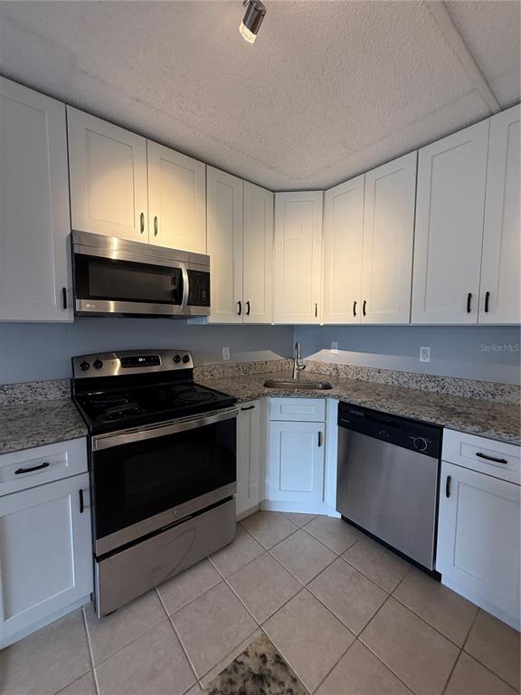 A kitchen features white cabinets, stainless steel appliances, and granite countertops — 927 S PINE RIDGE CIRCLE UNIT G2, SANFORD, FL