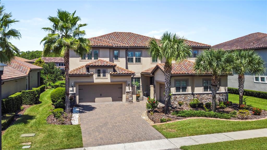 A two-story suburban house with a tile roof, stone accents, and a paved driveway — 10938 SAVONA WAY, ORLANDO, FL