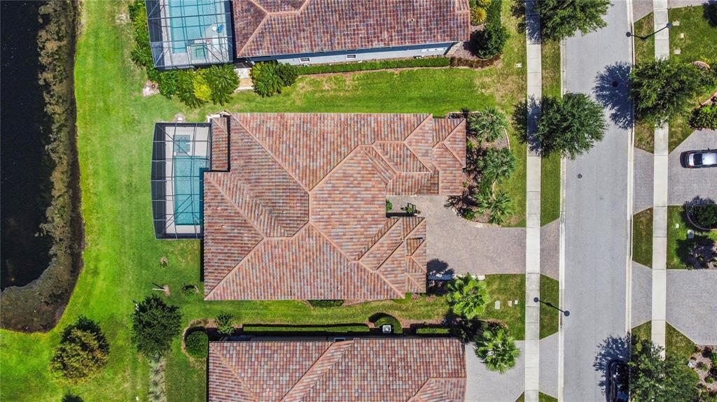 An aerial view shows a house with a tiled roof, a pool cage, and a driveway — 10938 SAVONA WAY, ORLANDO, FL