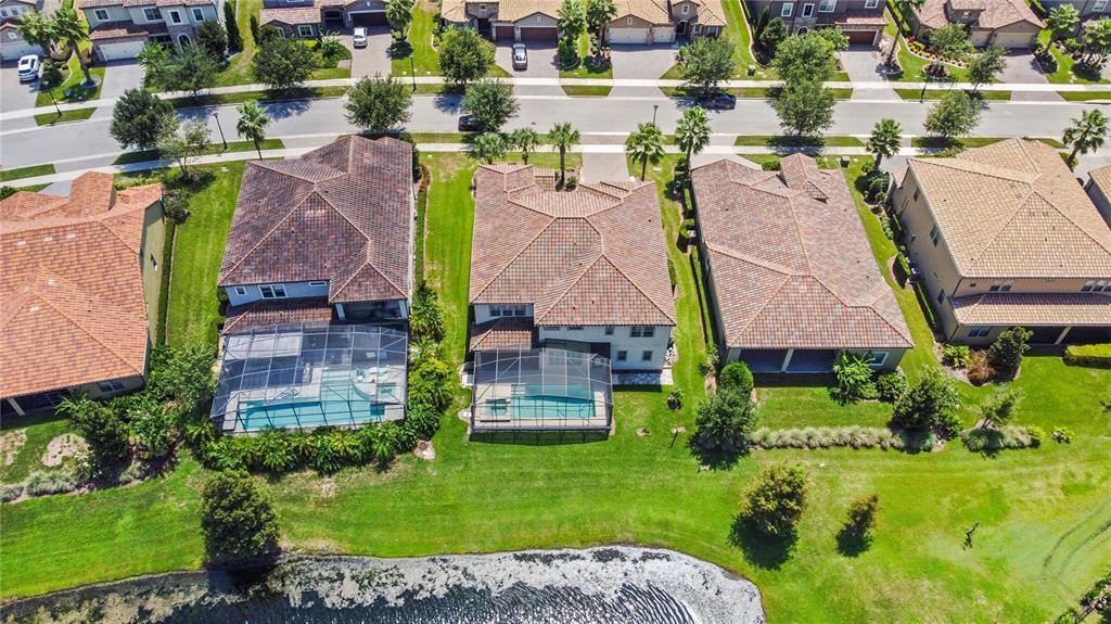 An aerial view shows three suburban houses with tiled roofs, screened-in pools, and grassy backyards — 10938 SAVONA WAY, ORLANDO, FL
