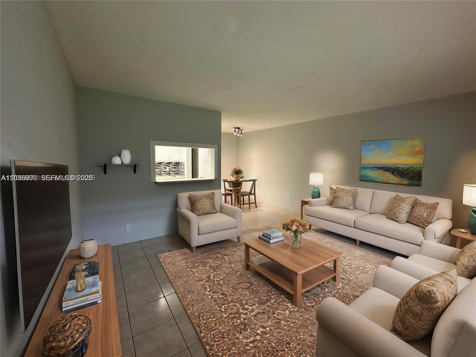 A living room features a beige sofa, armchair, area rug, and a kitchen pass-through window — 2916 Funston St # 47A, Hollywood FL 33020, HOLLYWOOD, FL