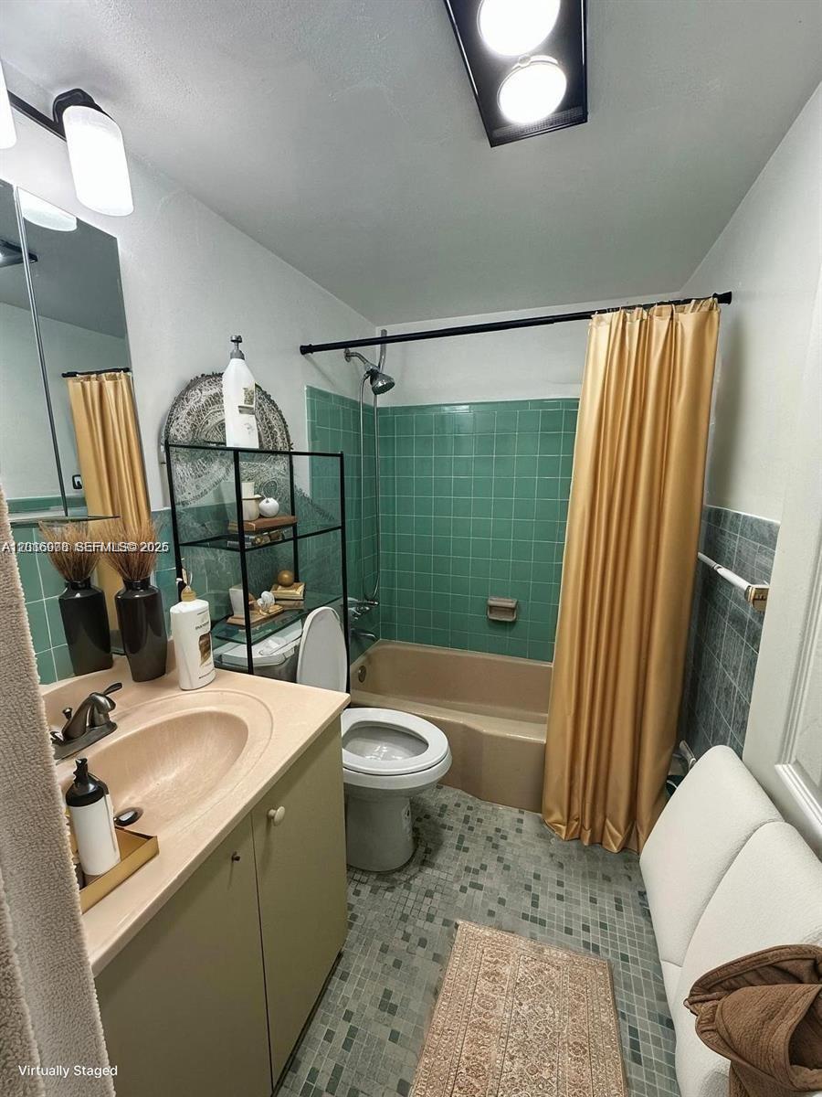 A bathroom features a green tiled shower surround, a beige tub, and a vanity — 2916 Funston St # 47A, Hollywood FL 33020, HOLLYWOOD, FL
