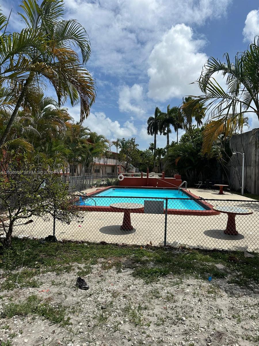A rectangular swimming pool is enclosed by a chain-link fence with palm trees nearby — 2916 Funston St # 47A, Hollywood FL 33020, HOLLYWOOD, FL