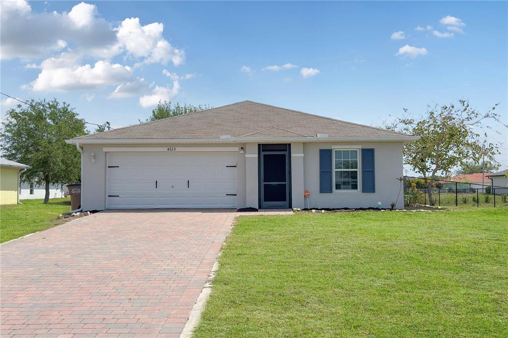 A single-story suburban house features a two-car garage, a paved driveway, and blue shutters — 4323 NE 21ST AVENUE, CAPE CORAL, FL
