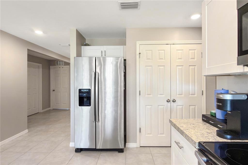A kitchen features stainless steel appliances, white cabinetry, and light-colored tile flooring — 4323 NE 21ST AVENUE, CAPE CORAL, FL