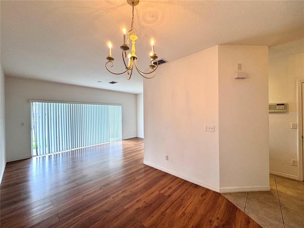 A dining area features wood-look flooring, a chandelier, and a large window with vertical blinds — 10735 SAVANNAH WOOD DRIVE UNIT 208, ORLANDO, FL