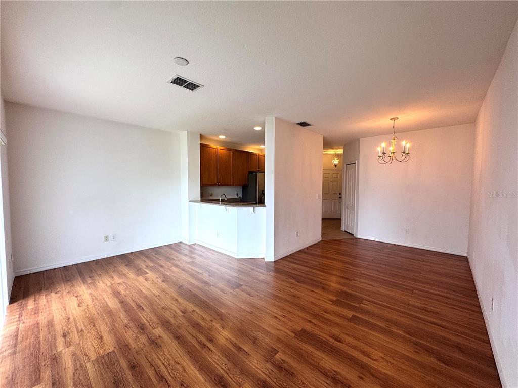 An open-concept living and dining area features wood-look flooring and a kitchen with wooden cabinets — 10735 SAVANNAH WOOD DRIVE UNIT 208, ORLANDO, FL