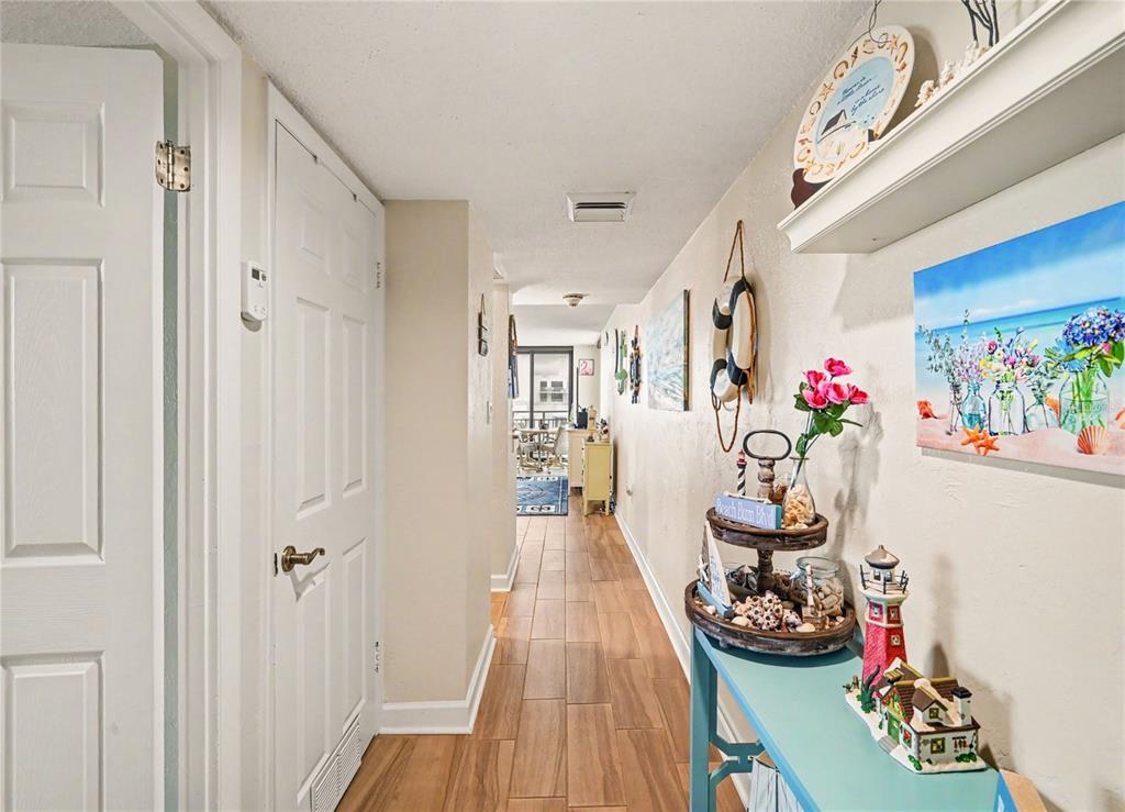 A hallway with wood-look tile flooring leads toward a bright room with a balcony — 3051 S ATLANTIC AVENUE UNIT V060, DAYTONA BEACH SHORES, FL