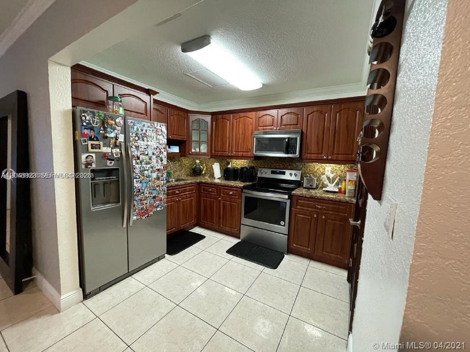 A kitchen features dark wood cabinets, stainless steel appliances, and light-colored tile flooring — 12860 SW 43rd Dr # B, Miami FL 33175, MIAMI, FL