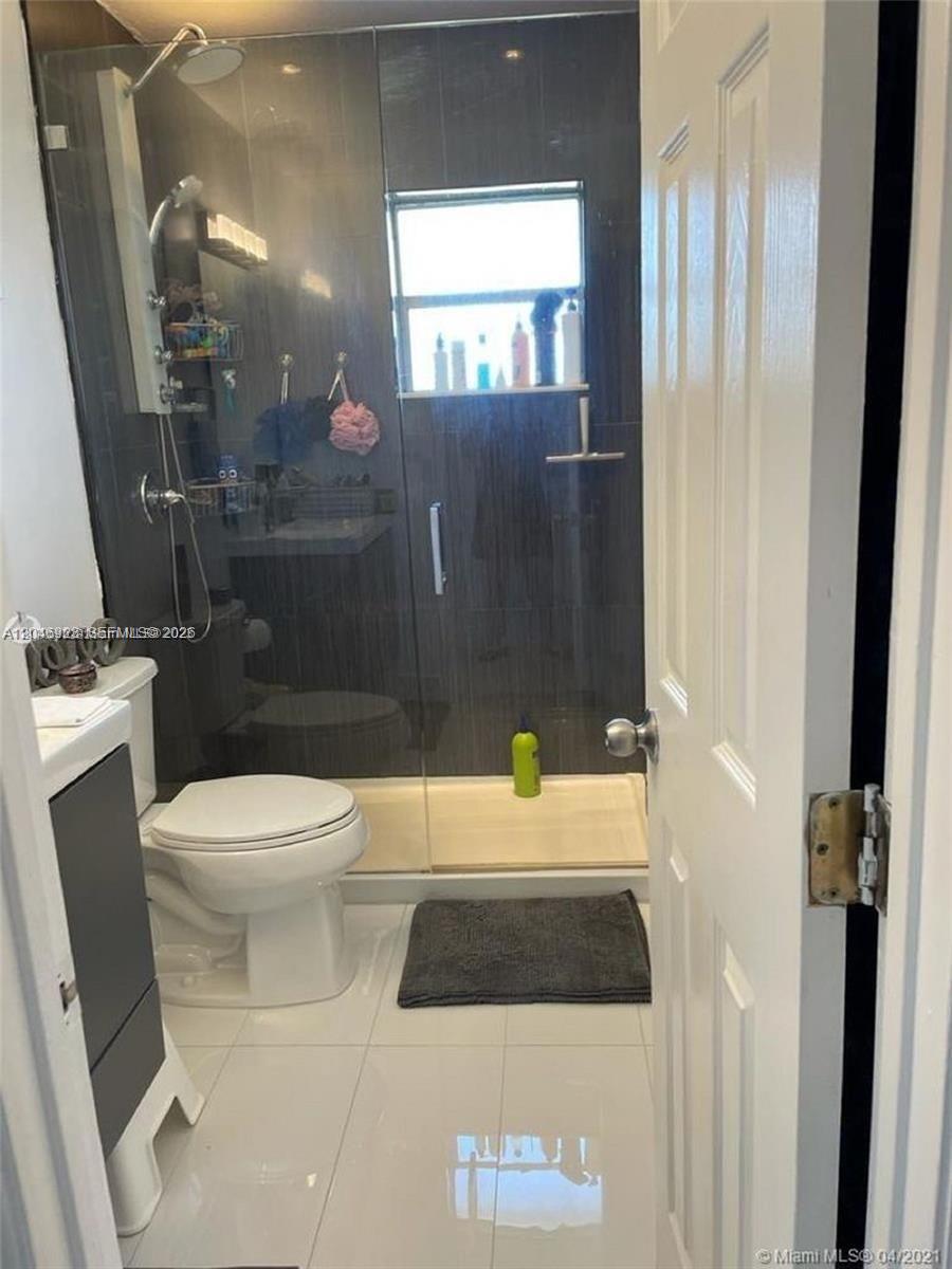 A bathroom features a glass-enclosed shower, a white toilet, and a vanity with white tiles — 12860 SW 43rd Dr # B, Miami FL 33175, MIAMI, FL