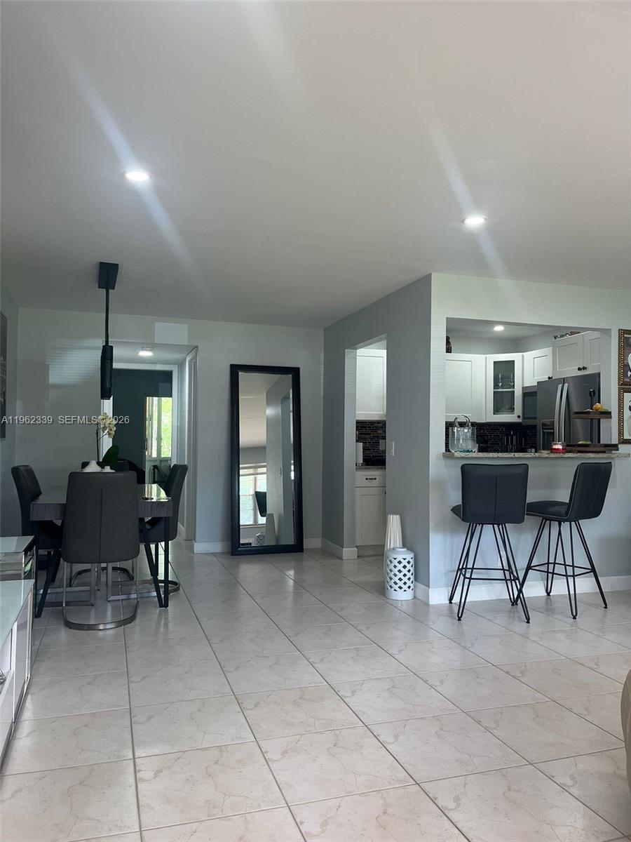 A dining area and kitchen breakfast bar feature gray chairs, tile flooring, and recessed lighting — 35 Camden # B, West Palm Beach FL 33417, WEST PALM BEACH, FL