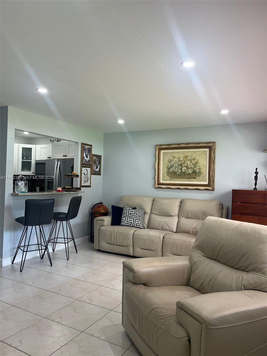 A living room features a beige leather sofa, matching armchair, and a kitchen breakfast bar — 35 Camden # B, West Palm Beach FL 33417, WEST PALM BEACH, FL