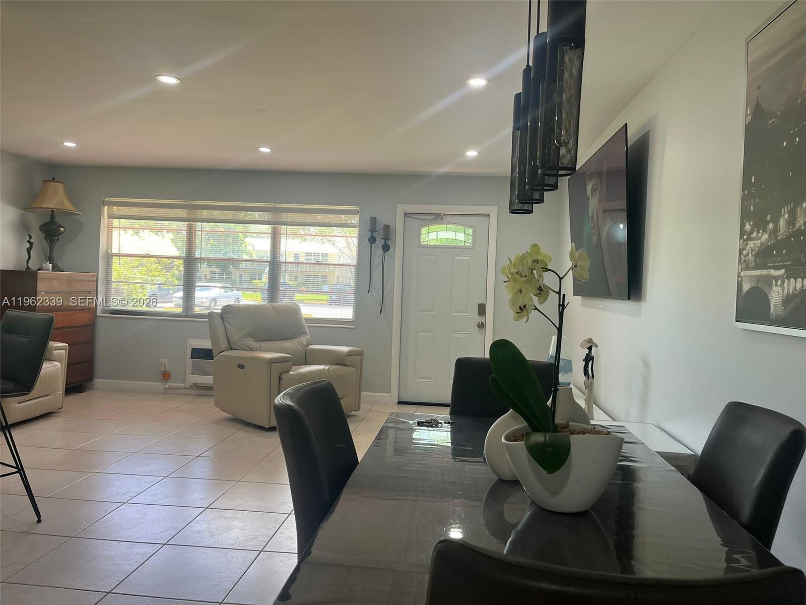 A dining area with a dark table and chairs sits adjacent to a living space — 35 Camden # B, West Palm Beach FL 33417, WEST PALM BEACH, FL