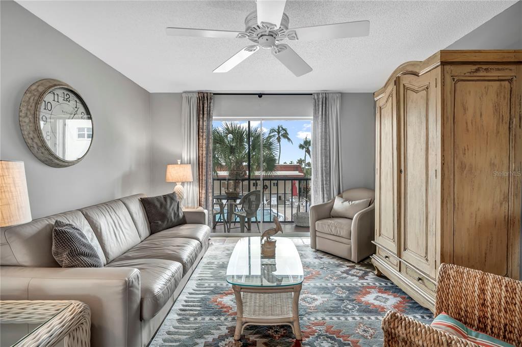 A living room features a leather sofa, a glass coffee table, and a large armoire — 915 BEACH ROAD UNIT 216, SARASOTA, FL