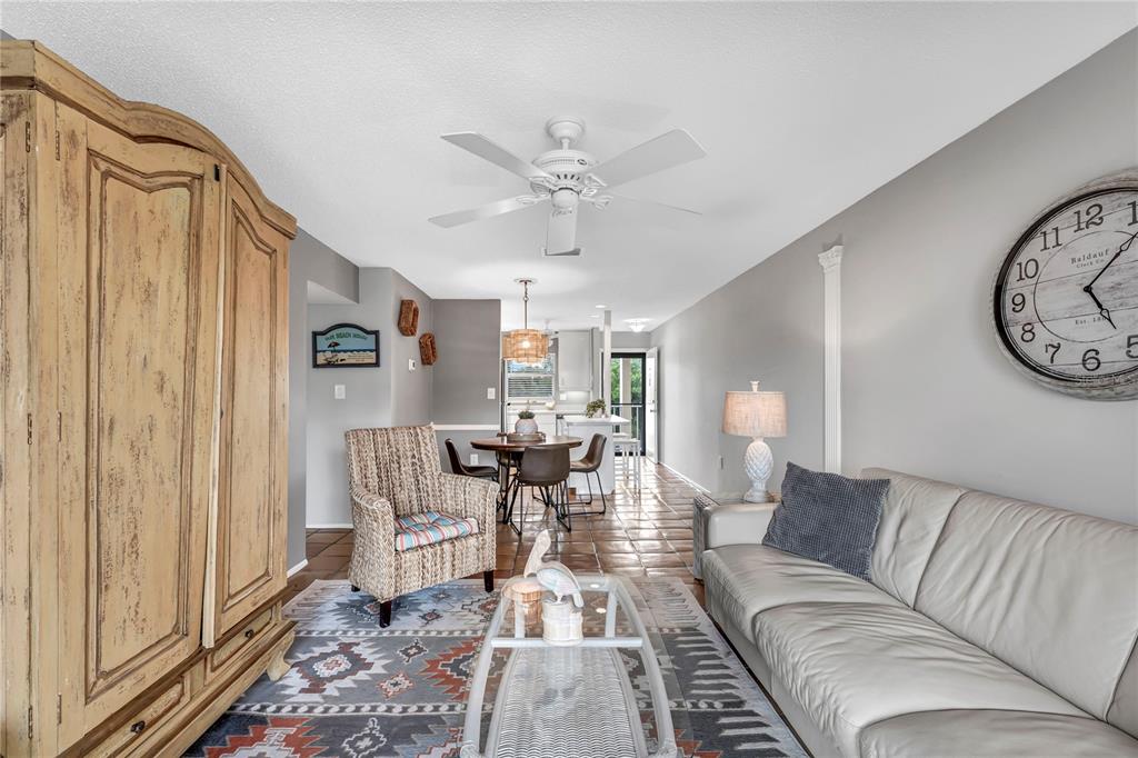 A living room with a large wooden armoire, a sofa, and an adjacent dining area — 915 BEACH ROAD UNIT 216, SARASOTA, FL