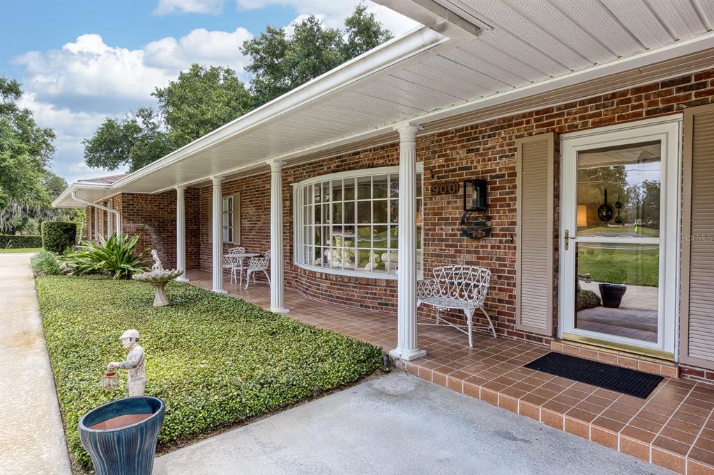 A brick house exterior features a covered porch with white columns and a bay window — 900 N CITRUS AVENUE, HOWEY IN THE HILLS, FL
