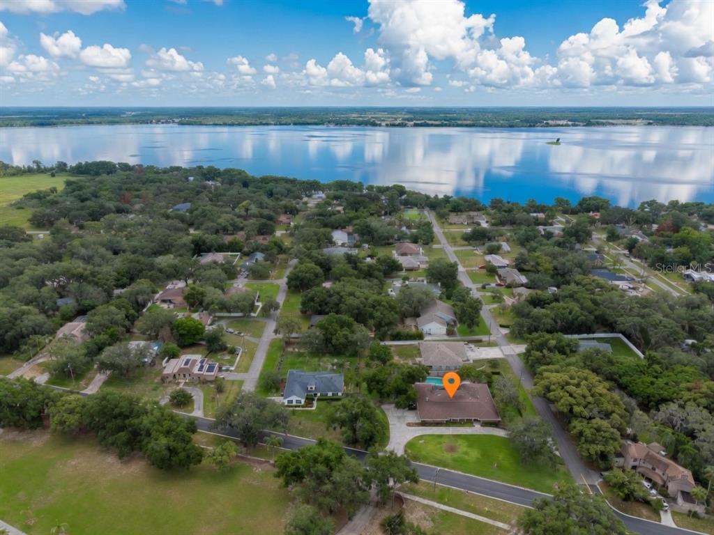 An aerial view shows a residential neighborhood with a large lake in the background — 900 N CITRUS AVENUE, HOWEY IN THE HILLS, FL