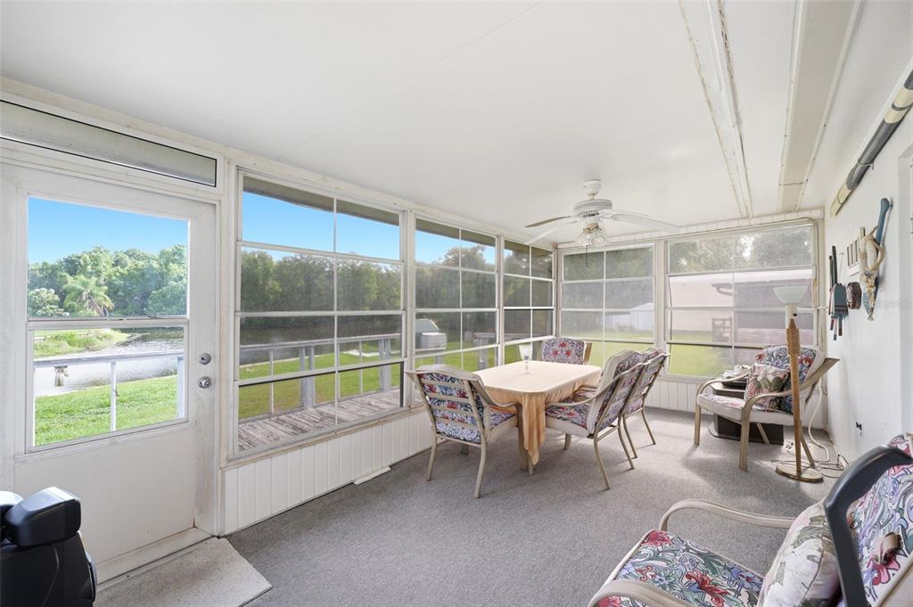 A sunroom with carpeted floors, a dining set, and large windows overlooking a grassy yard — 1830 S MANDARIN TERRACE, INVERNESS, FL
