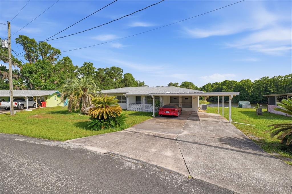 A single-story house with a carport, a red car, and a grassy yard — 1830 S MANDARIN TERRACE, INVERNESS, FL