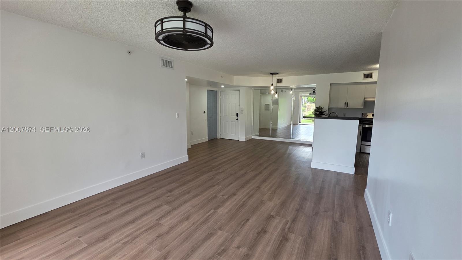 An open-concept living area features wood-look flooring, a ceiling fan, and an adjacent kitchen — 12136 Saint Andrews Pl # 108, Miramar FL 33025, MIRAMAR, FL