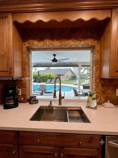 A kitchen sink with a faucet overlooks a backyard swimming pool through a large window — 1903 NW 79th Ave, Margate FL 33063, MARGATE, FL