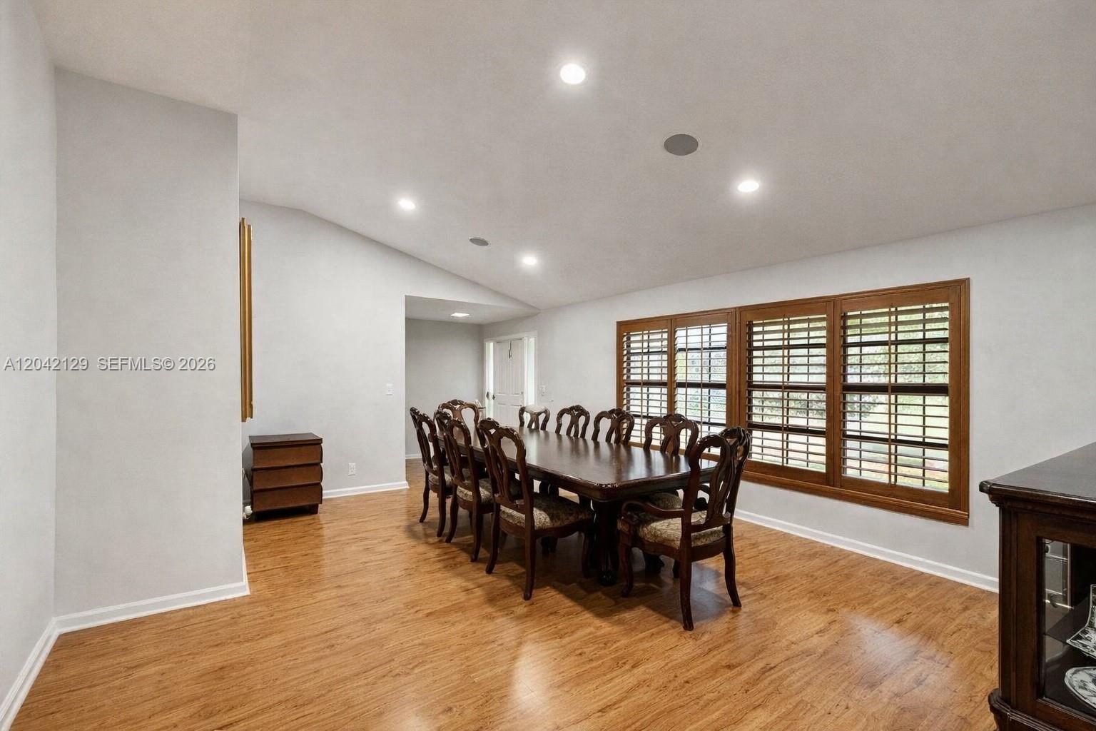 A dining room features a long wooden table with chairs, wood flooring, and shuttered windows — 1903 NW 79th Ave, Margate FL 33063, MARGATE, FL