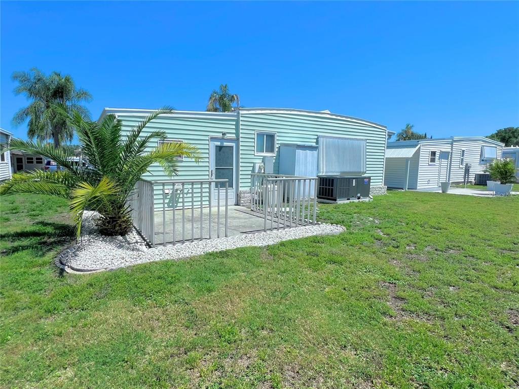 A light green mobile home features a small concrete patio with a white metal railing — 1100 BELCHER ROAD S UNIT 772, LARGO, FL