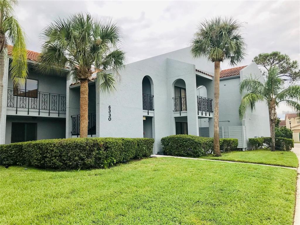 A two-story light blue stucco apartment building with palm trees and a manicured lawn — 6330 GRAND BAHAMA CIRCLE UNIT C, TAMPA, FL