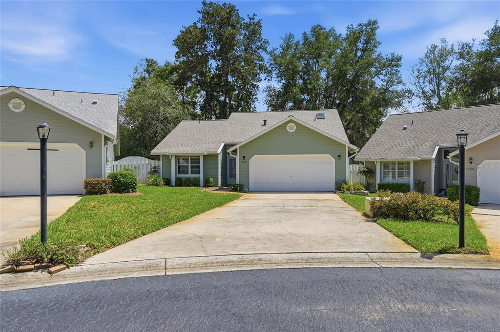 A single-story house with light green siding, a two-car garage, and a concrete driveway — 10521 NW 36TH PLACE, GAINESVILLE, FL