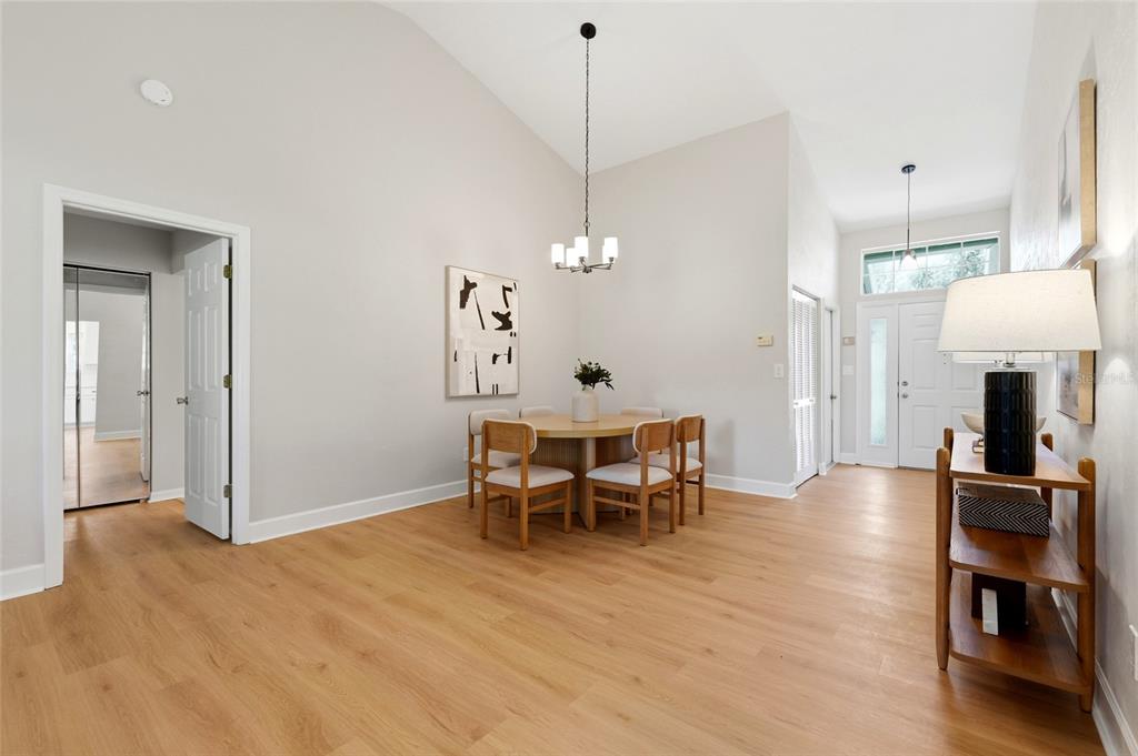 A dining area with light wood floors, a round table, and a vaulted ceiling — 10521 NW 36TH PLACE, GAINESVILLE, FL