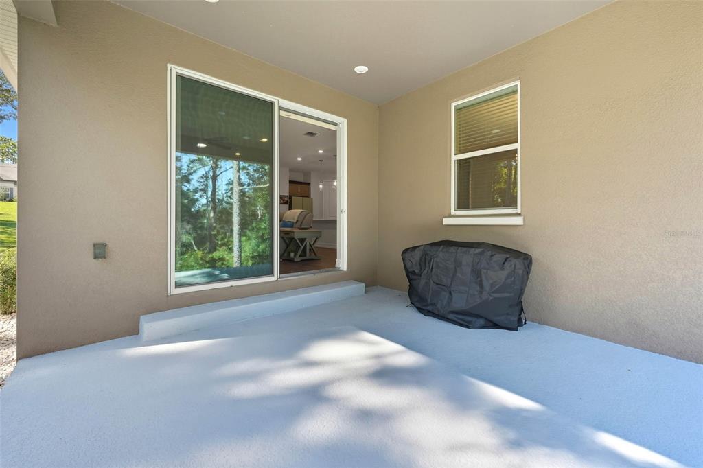 A covered concrete patio features a sliding glass door, a single window, and a grill cover — 5361 N PEPPERMINT DRIVE, BEVERLY HILLS, FL