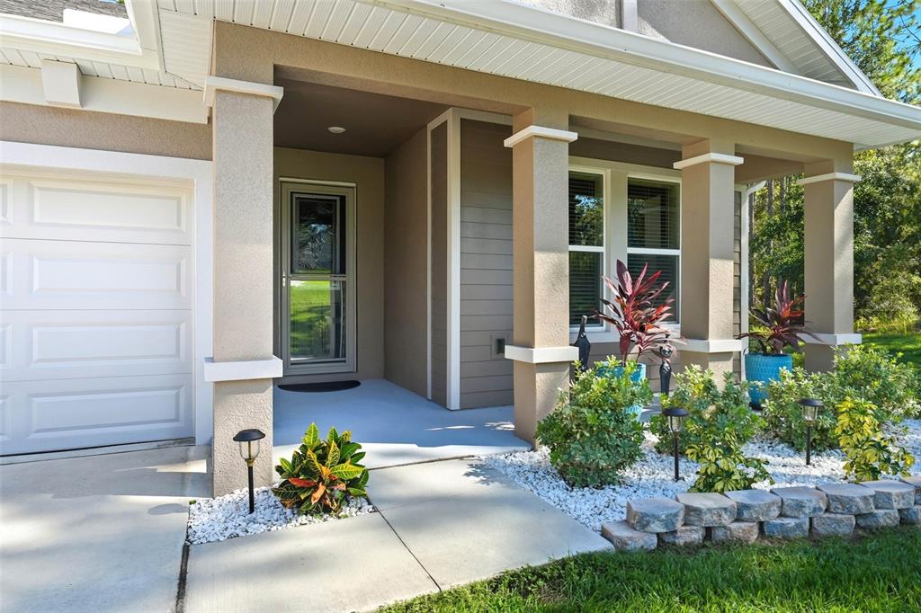 A covered front porch features square columns, a glass storm door, and landscaped garden beds — 5361 N PEPPERMINT DRIVE, BEVERLY HILLS, FL