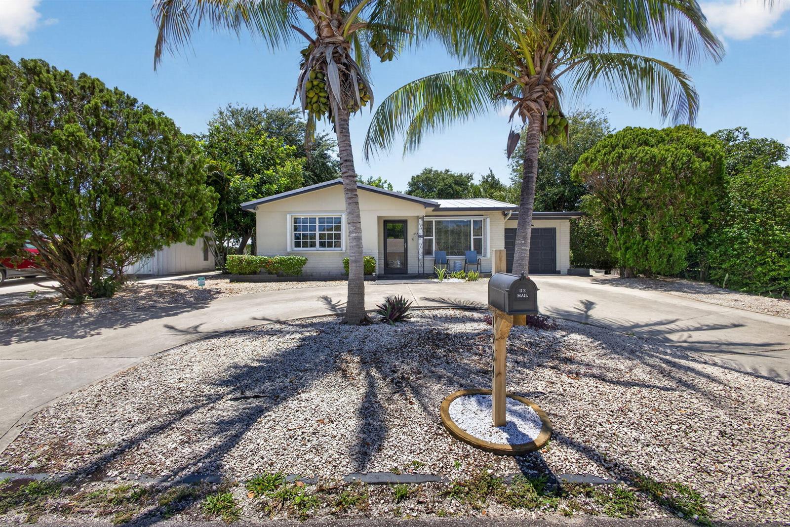 A single-story house with a circular driveway, palm trees, and a gravel front yard — 1964 Circle Drive, North Palm Beach FL 33408, NORTH PALM BEACH, FL