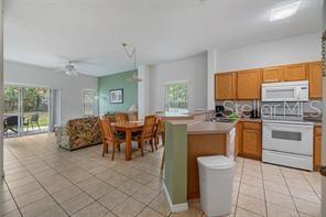 An open-concept kitchen and dining area features light wood cabinets, tile flooring, and sliding doors — 1057 PARK RIDGE CIRCLE, KISSIMMEE, FL