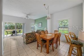 An open-concept dining and living area features tile flooring, a green accent wall, and patio access — 1057 PARK RIDGE CIRCLE, KISSIMMEE, FL