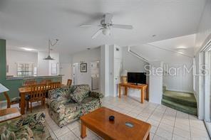 A living room with a floral sofa, wooden coffee table, dining area, and tiled flooring — 1057 PARK RIDGE CIRCLE, KISSIMMEE, FL