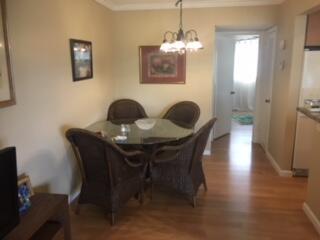 A dining area features a glass-topped table with four wicker chairs and a chandelier — 630 Snug Harbor Drive # C14, Boynton Beach FL 33435, BOYNTON BEACH, FL