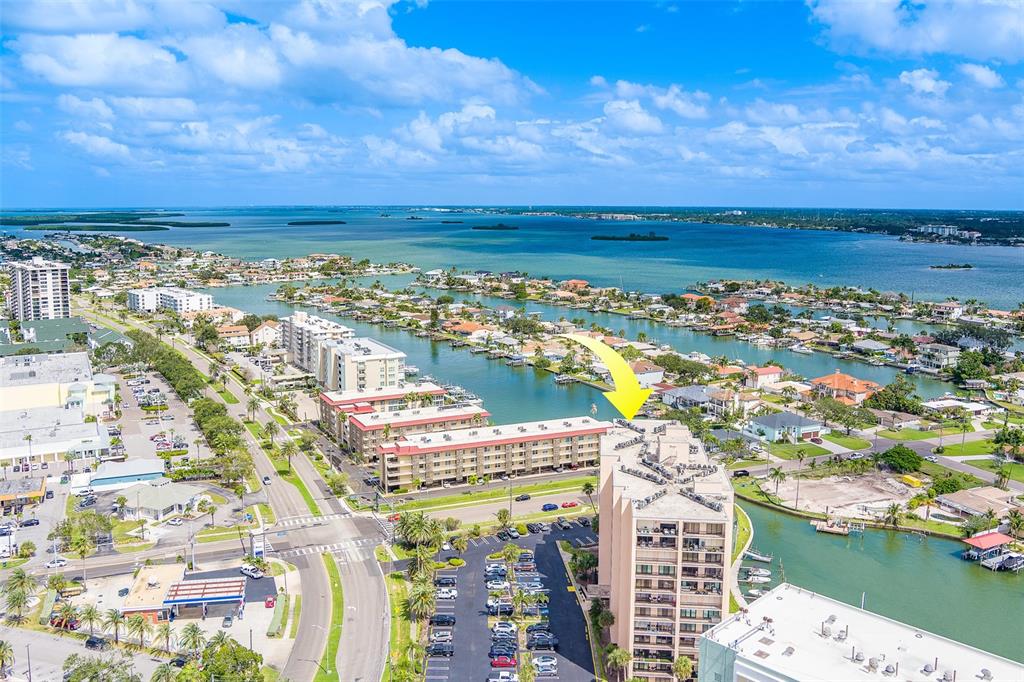 An aerial view shows a multi-story apartment building with a yellow arrow pointing toward it — 51 ISLAND WAY UNIT 101, CLEARWATER BEACH, FL