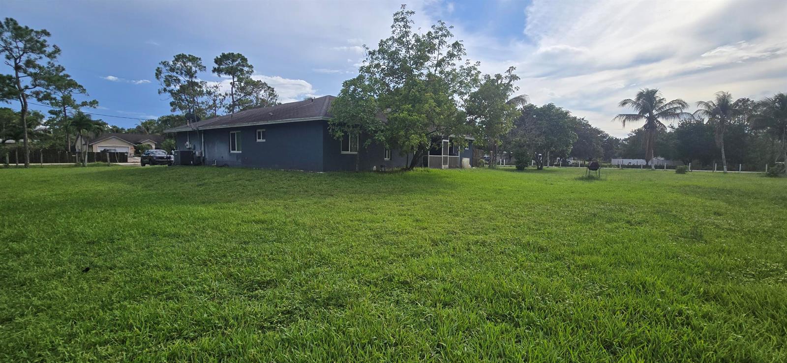 A view of the side and rear exterior of a dark-colored house with a large lawn — 17999 N 46th Court N, FL 33470, FL