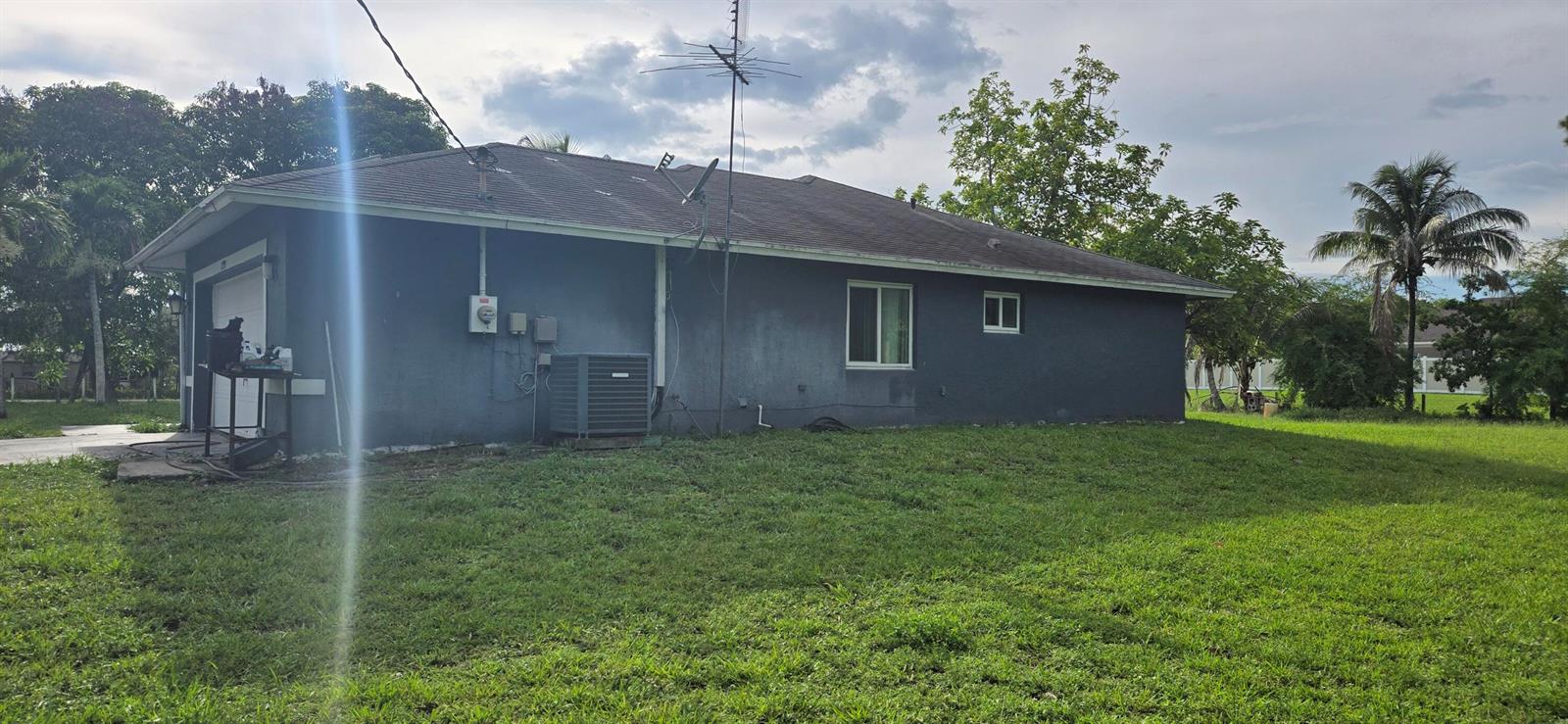 The exterior side view of a gray house features a garage, HVAC unit, and antenna — 17999 N 46th Court N, FL 33470, FL