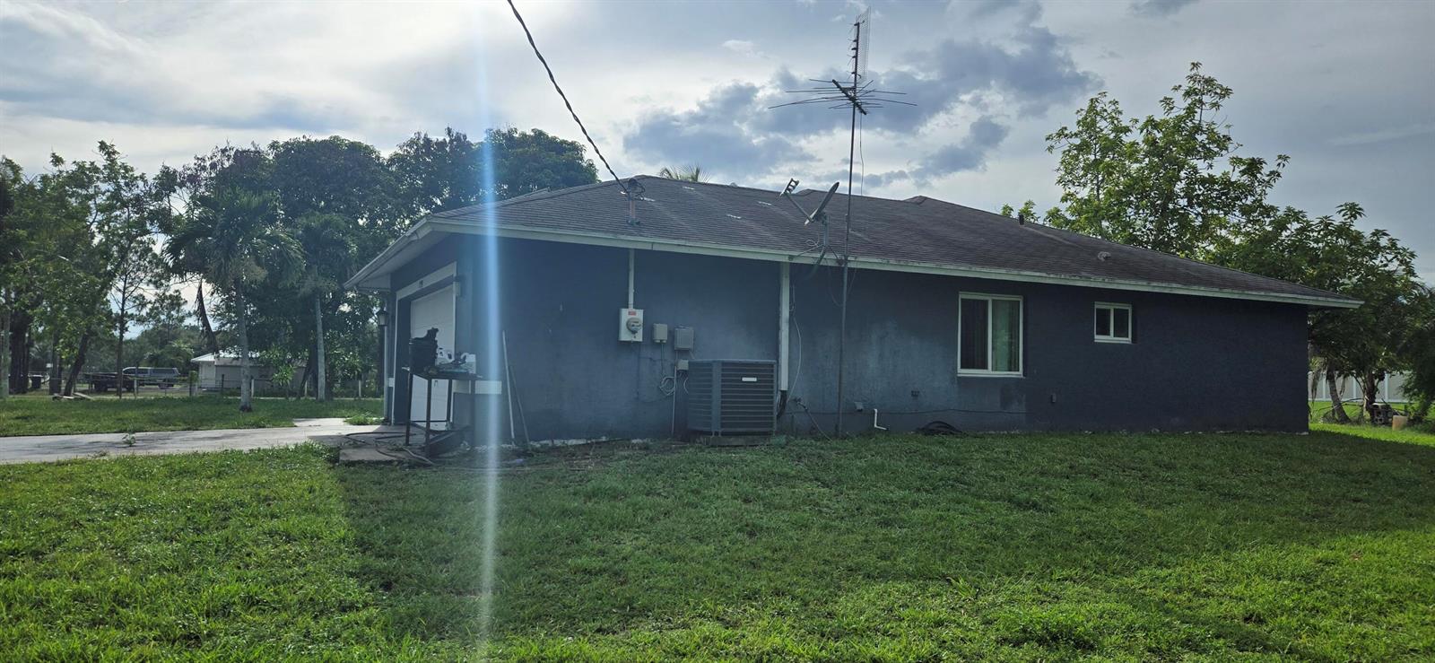 The exterior of a single-story house with a gray stucco finish and a garage — 17999 N 46th Court N, FL 33470, FL